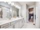 Elegant bathroom featuring double sinks, a large mirror with modern lighting, and a view into the walk-in closet at 13437 Waterthrush St, Parker, CO 80134