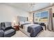 Comfortable bedroom featuring a large bed, tufted headboard, a sitting chair, and natural light from a window at 13437 Waterthrush St, Parker, CO 80134