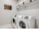 Bright laundry room featuring a modern washer and dryer set, storage shelves, and neutral decor at 13437 Waterthrush St, Parker, CO 80134