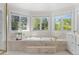 Soaking tub with marble surround is nestled beneath three windows providing natural light and peaceful views at 5390 S Boston St, Greenwood Village, CO 80111