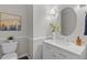 Updated bathroom featuring a marble countertop vanity, oval mirror, and decorative painting at 5390 S Boston St, Greenwood Village, CO 80111