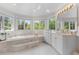 Sunlit bathroom features a marble soaking tub with jets nestled between bright windows overlooking lush greenery at 5390 S Boston St, Greenwood Village, CO 80111