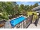 An eye-level view from a balcony overlooks a sparkling pool surrounded by lush greenery and a fenced-in yard at 5390 S Boston St, Greenwood Village, CO 80111