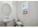 Modern half bathroom featuring a pedestal sink, toilet, and a window for natural light at 1366 Penner Dr, Erie, CO 80026