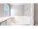 Bright bathroom with a large tiled bathtub and a window offering natural light at 15926 Butterwort Cir, Parker, CO 80134