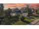 Inviting home with manicured lawn, mature trees, and a colorful sunset backdrop at 15926 Butterwort Cir, Parker, CO 80134