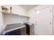 Functional laundry room with a modern washer and dryer, plus overhead storage shelf at 15926 Butterwort Cir, Parker, CO 80134