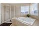 Bright bathroom with a large soaking tub next to a large sunny window and a glass shower at 10914 W Coco Pl, Littleton, CO 80127