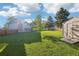 Expansive backyard with lush lawn, storage shed, and mature trees, offering plenty of space for recreation at 4933 S Xenon Ct, Morrison, CO 80465