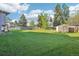 Spacious backyard with a wooden fence, large green space, and a shed for storage at 4933 S Xenon Ct, Morrison, CO 80465