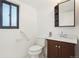 Bathroom with a dark wood vanity, updated fixtures, and a dark trimmed window at 4933 S Xenon Ct, Morrison, CO 80465