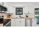 Modern kitchen with white cabinets, stainless steel appliances, butcher block countertops, black accents, and a large window at 4933 S Xenon Ct, Morrison, CO 80465