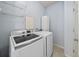 Functional laundry room with modern washer and dryer, storage cabinets, and wire shelves at 15612 E 96Th Way # 20H, Commerce City, CO 80022