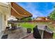 Charming backyard featuring a patio with seating under an awning, a grill, and a well-maintained lawn at 8475 W 74Th Dr, Arvada, CO 80005