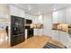 Modern kitchen featuring white cabinets, hardwood floors, a stylish rug, and stainless steel appliances at 8475 W 74Th Dr, Arvada, CO 80005