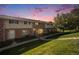 Sunset view of a brick townhome with a landscaped yard and manicured lawn at 9272 E Mansfield Ave, Denver, CO 80237