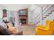 Open-concept living room featuring a brick fireplace, a staircase, and neutral colored walls at 12142 Bannock Cir # B, Denver, CO 80234