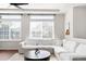 Cozy living room showcasing a white sectional sofa, large windows, and a wooden coffee table on a patterned rug at 21925 E 44Th Pl, Aurora, CO 80019
