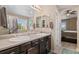 Primary bathroom featuring double sinks, framed mirrors, and an attached bedroom at 5161 Chicory Cir, Brighton, CO 80601