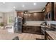 Well-lit kitchen with dark wood cabinets, stainless steel appliances, and a granite countertop at 5161 Chicory Cir, Brighton, CO 80601