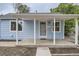 Close up of a blue home's front porch with white columns, a covered entrance, and fresh landscaping at 233 N 10Th Ave, Brighton, CO 80601