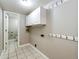 Functional laundry room with tile flooring, overhead cabinets, and convenient coat hooks at 4894 E Ashton Ave, Castle Rock, CO 80104