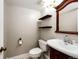 Elegant powder room features a dark wood vanity with decorative mirror and floating shelves at 4894 E Ashton Ave, Castle Rock, CO 80104