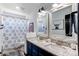 Bathroom featuring a double vanity with granite countertops, stylish mirrors, and a patterned shower curtain at 25338 E Costilla Pl, Aurora, CO 80016