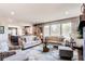 Bright living room featuring stylish sofas, a glass coffee table, and an open-concept view into the kitchen at 25338 E Costilla Pl, Aurora, CO 80016