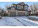 Two-story home with a brick and siding exterior, two car garage, and a snow covered front yard at 11701 Bent Oaks St, Parker, CO 80138