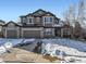 Two-story home with a brick and siding exterior, two car garage, and a snow covered front yard at 11701 Bent Oaks St, Parker, CO 80138