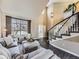 Open living room with hardwood floors, gray sectional sofa, and a curved staircase at 11701 Bent Oaks St, Parker, CO 80138