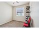 A simple, carpeted bedroom with a window and a rolling desk chair at 2212 Tamarac St, Denver, CO 80238