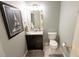 Small, quaint bathroom with a vanity, toilet, framed art and neutral wall color at 7627 Halleys Dr, Littleton, CO 80125