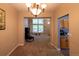 Formal dining area with view to kitchen, with neutral walls, plush carpet, chandelier, and a large window at 7627 Halleys Dr, Littleton, CO 80125