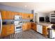 Well-lit kitchen with wooden cabinets, stainless steel appliances, granite countertops, and views to the fireplace at 7627 Halleys Dr, Littleton, CO 80125