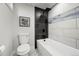 Modern bathroom featuring a black rainfall shower head, stylish grey tiling, and a sleek white tub at 9591 W Florida Pl, Lakewood, CO 80232