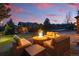 Inviting stone patio with comfortable seating area around a fire pit, perfect for outdoor gatherings at dusk at 6577 Esperanza Dr, Castle Pines, CO 80108