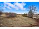 Expansive grassy backyard with a mature tree and wooden fence and views beyond at 6577 Esperanza Dr, Castle Pines, CO 80108