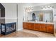 Primary bathroom with wood cabinets, dual vanity and corner fireplace at 6577 Esperanza Dr, Castle Pines, CO 80108
