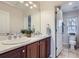 Well-lit bathroom with double sinks, wood cabinets, and a view of the toilet at 10148 E 29Th Dr, Denver, CO 80238