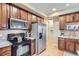 Well-equipped kitchen boasts wood cabinets, stainless steel appliances, and black cooktop at 10148 E 29Th Dr, Denver, CO 80238