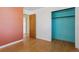 Bedroom with hardwood floors, a light orange accent wall, and an open closet at 1742 S Forest St, Denver, CO 80222
