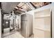 Unfinished basement features a refrigerator, shelving, and utilities at 2822 S Zenobia St, Denver, CO 80236