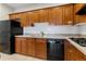 Well-lit kitchen features warm wood cabinetry, tile floor, and black appliances at 30 Garfield St # G, Denver, CO 80206