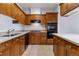 Well-lit kitchen features warm wood cabinetry, tile floor, and black appliances at 30 Garfield St # G, Denver, CO 80206