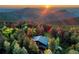 Stunning aerial view of mountain home surrounded by lush forest at sunset, offering seclusion and scenic beauty at 13416 Kuehster Rd, Littleton, CO 80127