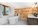 Modern bathroom featuring a standalone tub, wood accent wall, and stylish fixtures for a luxurious experience at 13416 Kuehster Rd, Littleton, CO 80127