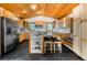 Well-lit kitchen featuring stainless steel appliances, light wood cabinets, island with seating, and black tile flooring at 13416 Kuehster Rd, Littleton, CO 80127