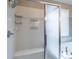 Close up of bright shower with white tile, a built-in bench, shelving, and glass door at 6265 S Ider Way, Aurora, CO 80016